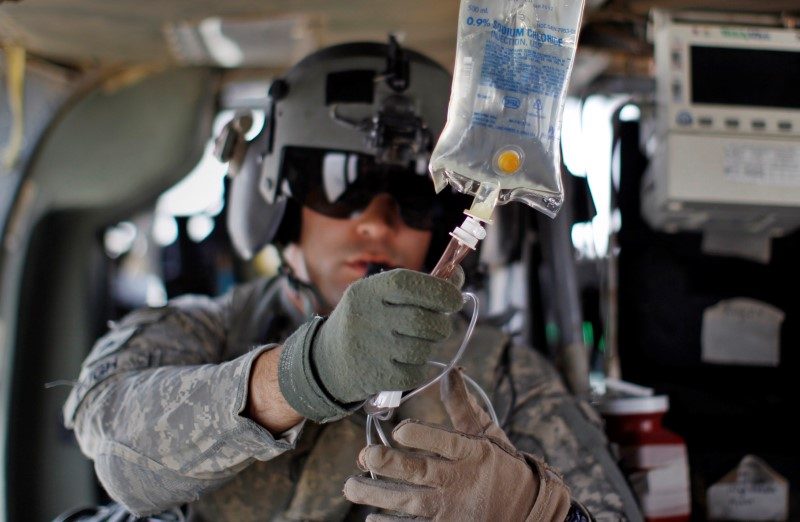 Flight medic U.S. Army Sgt Ian Bugh prepares an IV drip as his medevac helicopter team flies to pick up a wounded Marine, near the town of Marjah in Helmand Province, in this August 17, 2010 file photo. REUTERS/Bob Strong/Files