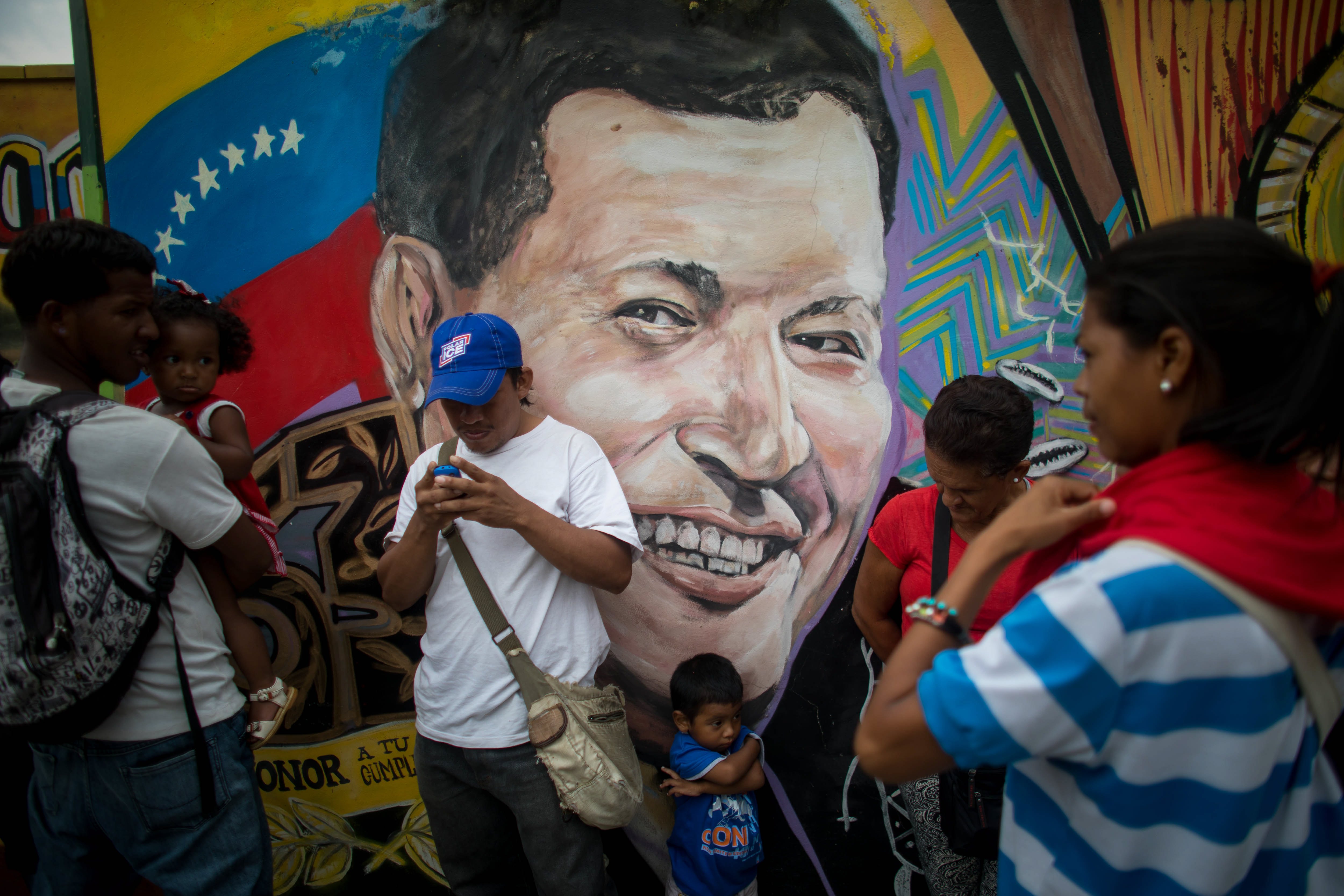 2018-03-05 18:06:00 epa06583354 People stand in front of wall with the image of late Venezuelan President Hugo Chavez in Caracas, Venezuela, 05 March 2018. Hugo Chavez, president of Venezuela between 1999 and 2013, died five years ago. EPA/MIGUEL GUTIERREZ
