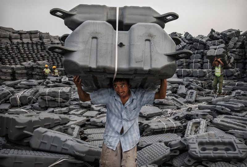 Een arbeider draagt een drijfplatform voor zonnepanelen bij de bouw van een zonnefarm in de Chinese provincie Anhui. Foto: Kevin Frayer/Getty Images