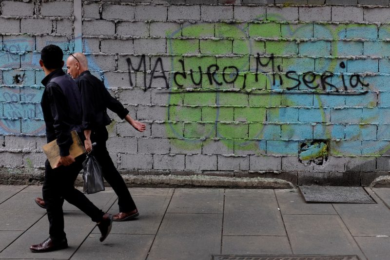 People walk past a graffiti that reads: 