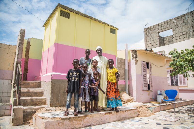 Malickane Gueye stands with his children in front of a newly constructed toilet at his home in Guinaw Rail Sud, Dakar, Senegal on September 25, 2018. 