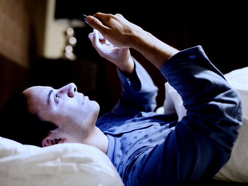 Man Using Phone in Bed