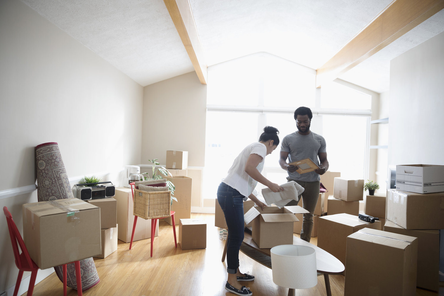 Young couple packing belongings in cardboard boxes, moving house
