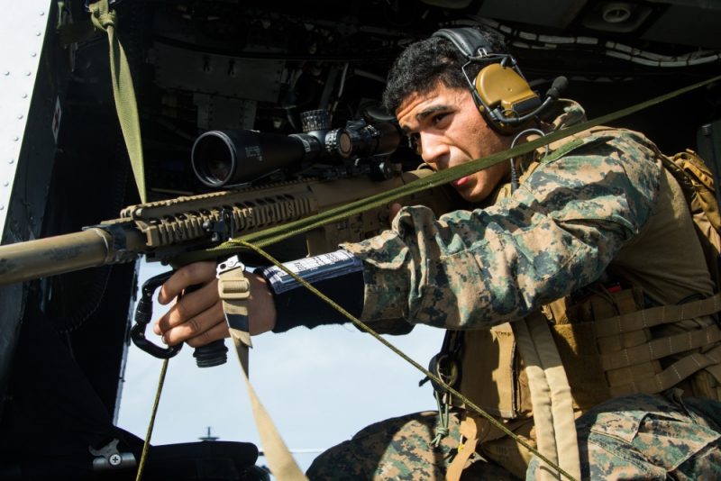 A lead scout sniper with the 31st Marine Expeditionary Unit's Maritime Raid Force, tests his Opposing V sniper support system on a UH-1Y Huey aboard the amphibious transport dock USS Green Bay (LPD 20) prior to a simulated visit, board, search and seizure of a ship, underway in the Coral Sea, July 7, 2019.