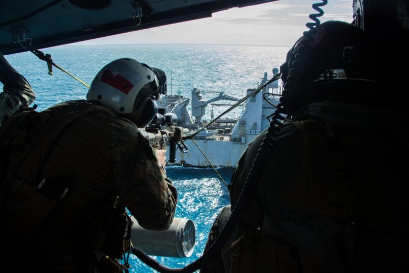 a lead scout sniper with the 31st Marine Expeditionary Unit's Maritime Raid Force, provides aerial sniper coverage during a simulated visit, board, search and seizure of the dock landing ship USS Ashland (LSD 48), underway in the Coral Sea, July 7, 2019.