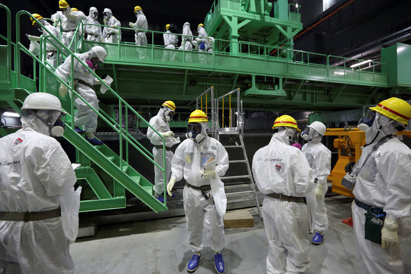 Members of the media and Tokyo Electric Power Co. (TEPCO) employees wearing protective suits and masks walk down the steps of a fuel handling machine on the spent fuel pool inside the No.4 reactor building at the tsunami-crippled TEPCO's Fukushima Daiichi nuclear power plant in Fukushima prefecture November 7, 2013.   REUTERS/Tomohiro Ohsumi/Pool/File Photo