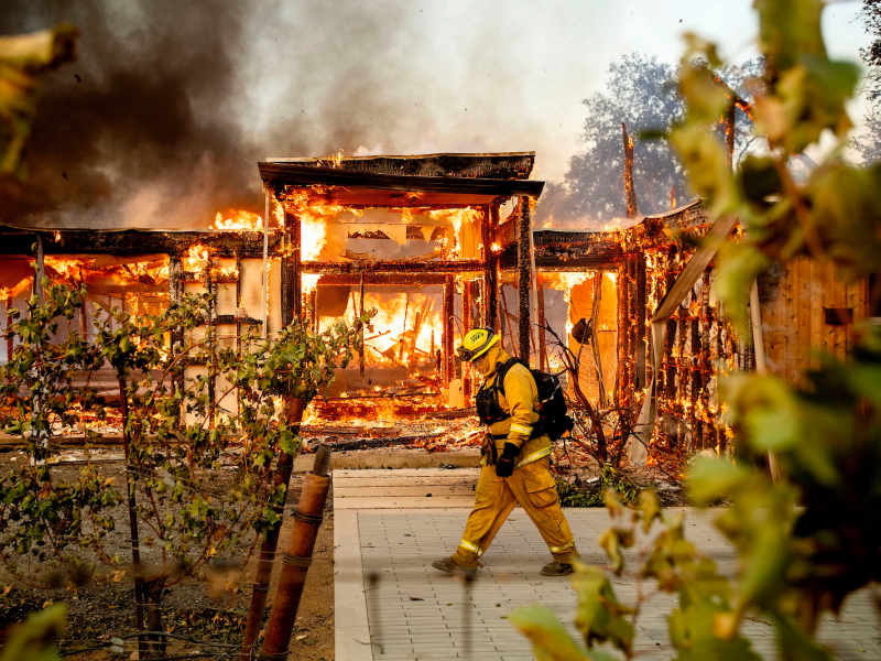 Woodbridge firefighter Joe Zurilgen passes a burning home as the Kincade Fire rages in Healdsburg, Calif., on Sunday, Oct 27, 2019.
