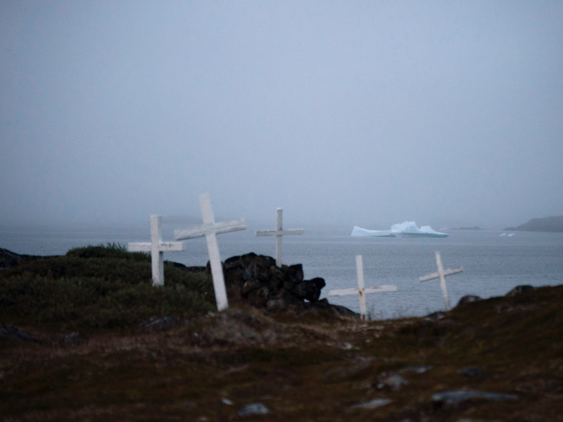 An iceberg floats near a cemetery in Kulusuk, Greenland, early Thursday, Aug. 15, 2019.