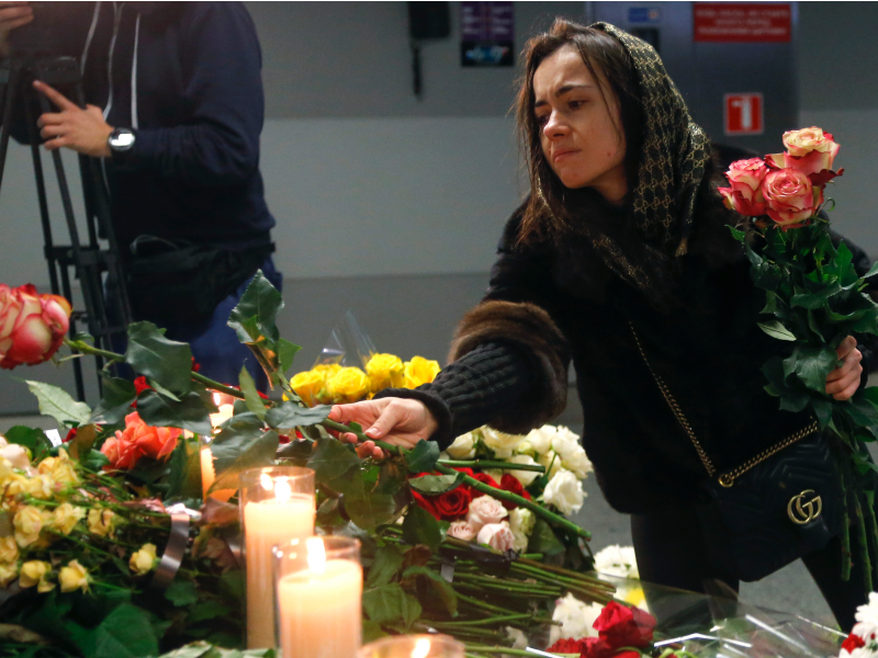 A woman lays flowers at a memorial of the flight crew members of the Ukrainian 737-800 plane that crashed on the outskirts of Tehran, at Borispil international airport outside in Kyiv, Ukraine, Saturday, Jan. 11, 2020. Ukraine's President Volodymyr Zelenskiy says that Iran must take further steps following its admission that one of its missiles shot down Ukrainian civilian airliner.  (AP Photo/Efrem Lukatsky)
