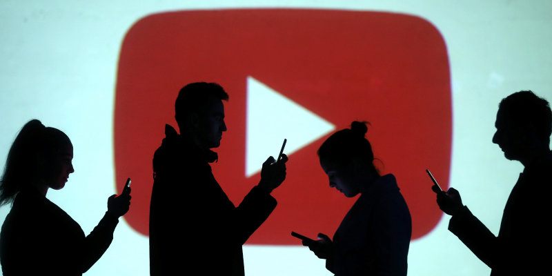 FILE PHOTO: Silhouettes of mobile users are seen next to a screen projection of Youtube logo in this picture illustration taken March 28, 2018.  REUTERS/Dado Ruvic/Illustration