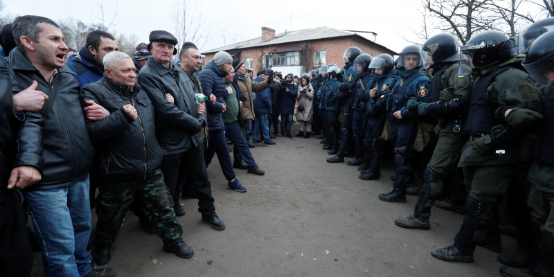 Demonstrators line up in front of Ukrainian law enforcement officers as they protest the arrival of a plane carrying evacuees from China's Hubei province hit by an outbreak of the novel coronavirus in the village of Novi Sanzhary in Poltava region, Ukraine February 20, 2020. Protesters blocked the road leading to a sanatorium where the evacuees are due to be held in quarantine for at least two weeks. REUTERS/Valentyn Ogirenko
