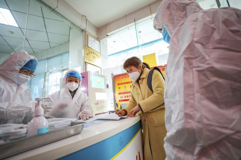 Medical workers in protective gear talk with a woman suspected of being ill with a coronavirus at a community health station in Wuhan in central China's Hubei Province, Monday, Jan. 27, 2020. China on Monday expanded sweeping efforts to contain a viral disease by extending the Lunar New Year holiday to keep the public at home and avoid spreading infection. (Chinatopix via AP)