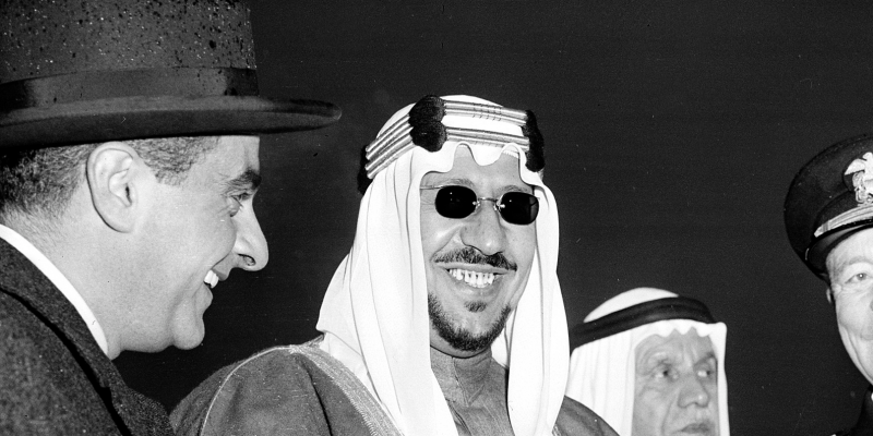U.S. Vice President Richard Nixon, right, and King Saud of Saudi Arabia pose at Washington National Airport, D.C., at the rain-swept ceremonies for the departing king after his state visit on Feb. 9, 1957. At right is the king's interpreter. Adm. Arthur Radford, chairman of the joint chiefs of staff, is at left. (AP Photo)