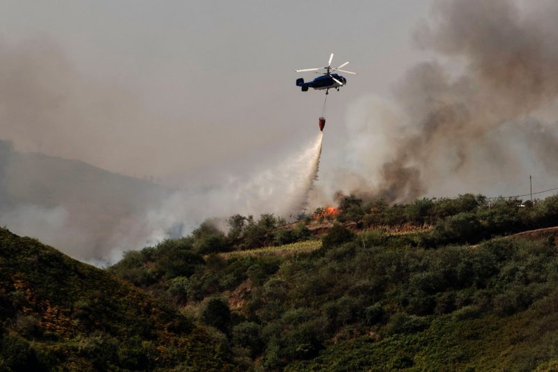 A helicopter operates over a wildfire in Canary Islands, Spain, Monday, Aug. 19, 2019.