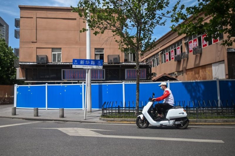 A man rides a scooter past the closed Huanan Seafood Wholesale Market in Wuhan, China, on May 19, 2020.