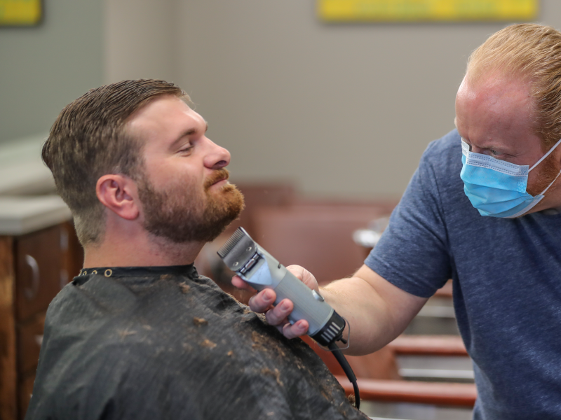 Barber and owner of Chris Edwards wears a mask and cuts the hair of customer David Boswell at Peachtree Battle Barber Shop in Atlanta on Friday, April 24, 2020. The first phase of Georgia Gov. Brian Kemp's plan to reopen Georgia during the coronavirus pandemic included haircut shops and gyms, though not all chose to open their doors. (John Spink/Atlanta Journal-Constitution via AP)