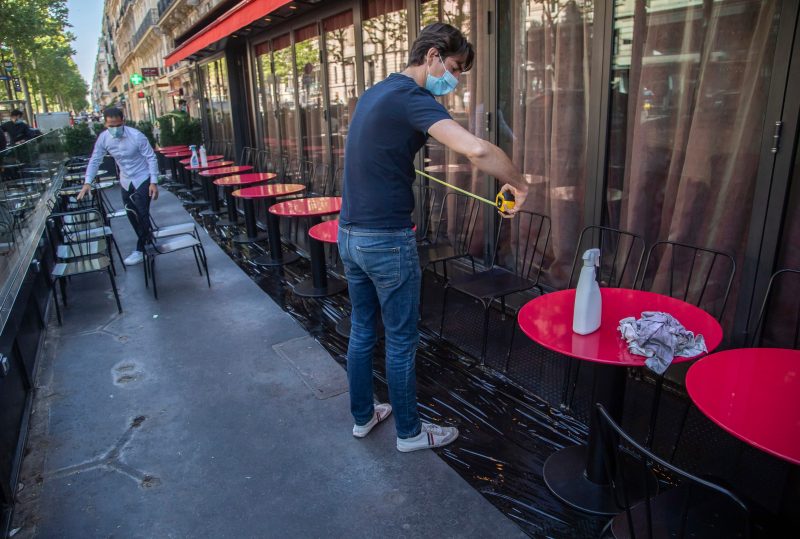 Pierre-Antoine Boureau handling a tape measure as he prepares the terrace of a restaurant in order to respect distancing to help curb the spread of the coronavirus in Paris, Monday, June 1, 2020. France is reopening its restaurants, bars and cafes starting tomorrow as the country eases most restrictions amid the coronavirus crisis. (AP Photo/Michel Euler)