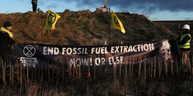 Demonstrators from Extinction Rebellion display a banner as a site security member looks on during a protest at Banks Group's open-cast coal mine in Bradley, County Durham, Britain February 26, 2020. REUTERS/Scott Heppell