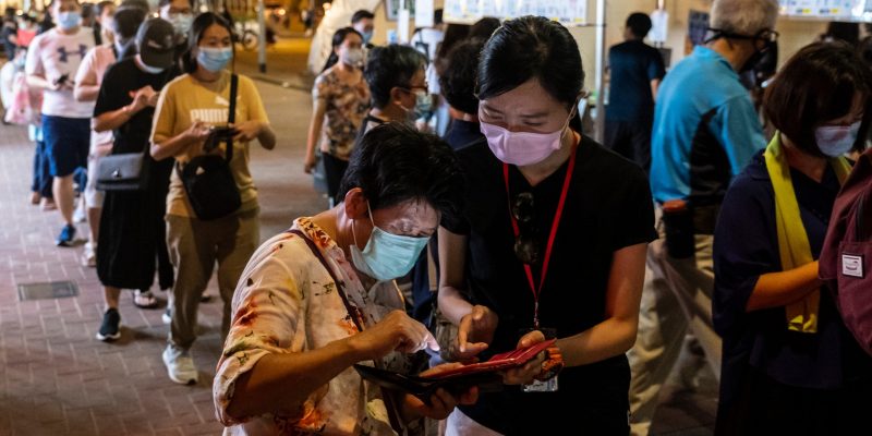 HONG KONG, CHINA - 2020/07/12: A volunteer assists a voter at a temporary polling station during an unofficial primary elections. (Photo by Chan Long Hei/SOPA Images/LightRocket via Getty Images)