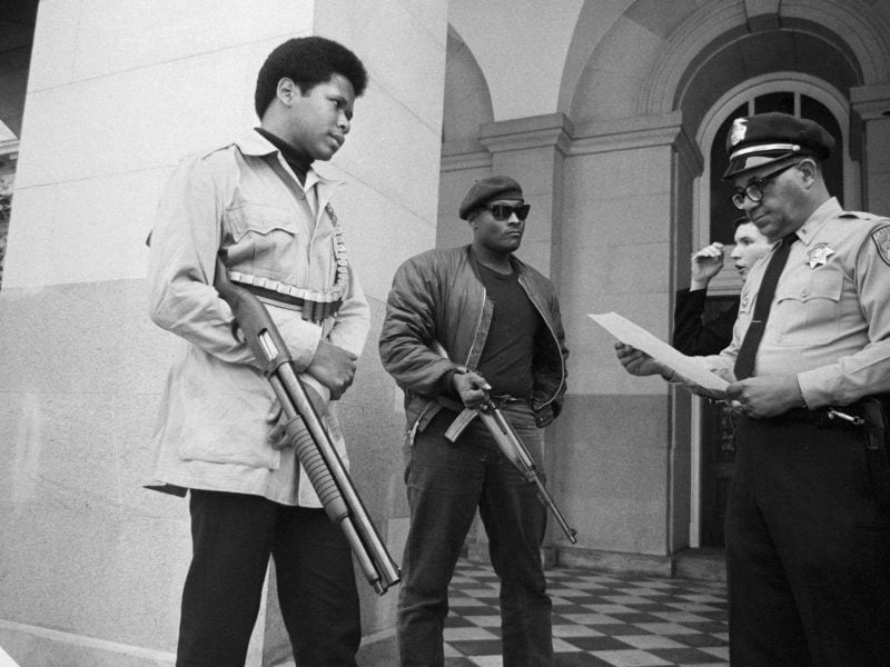 Two members of the Black Panther Party are met on the steps of the State Capitol in Sacramento, California, on May 2, 1967, by Police Lt. Ernest Holloway, who informs them they will be allowed to keep their weapons as long as they cause no trouble and do not disturb the peace.