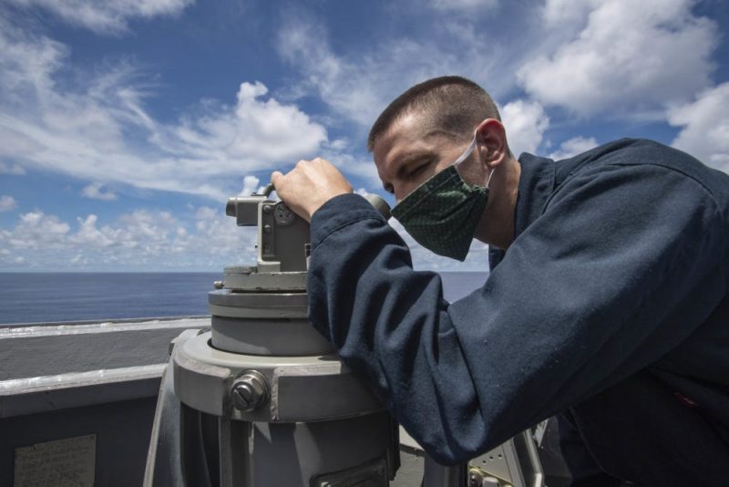 Logistics Specialist 2nd Class Paul Vance, from Lilburn, Ga., assigned to the Arleigh Burke-class guided-missile destroyer USS Ralph Johnson (DDG 114), scans the horizon using a telescopic alidade, July 14, near the Spratly Islands in the South China Sea