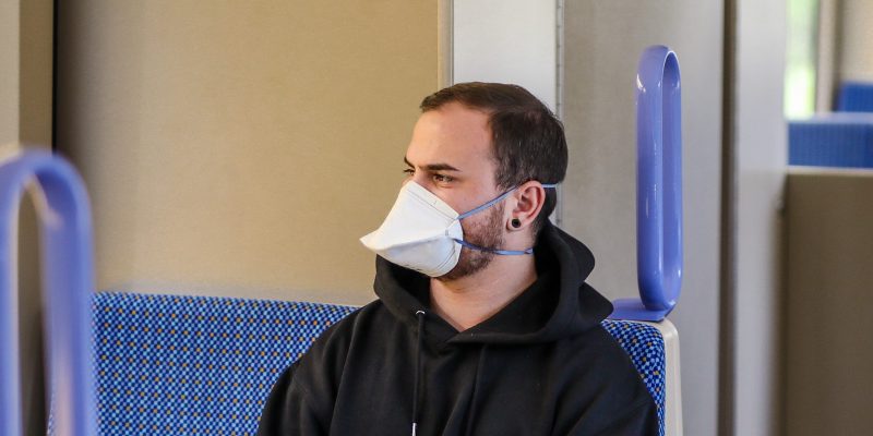 15 April 2020, Baden-Wuerttemberg, Stuttgart: ILLUSTRATION - A young man is wearing a FFP2 category respirator in a light rail vehicle (posed shot). An obligation to wear a mask for mouth and nose in public is being discussed as a possible measure to gradually ease the restrictions imposed to combat the coronavirus pandemic. Photo: Christoph Schmidt/dpa (Photo by Christoph Schmidt/picture alliance via Getty Images)