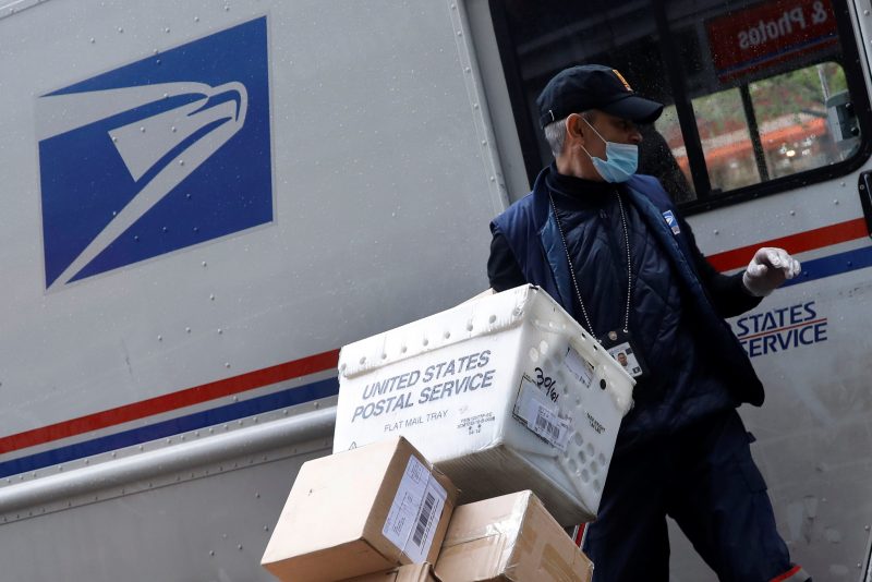 FILE PHOTO: A United States Postal Service (USPS) worker unloads packages from his truck in Manhattan during the outbreak of the coronavirus disease (COVID-19) in New York City, New York, U.S., April 13, 2020. REUTERS/Mike Segar