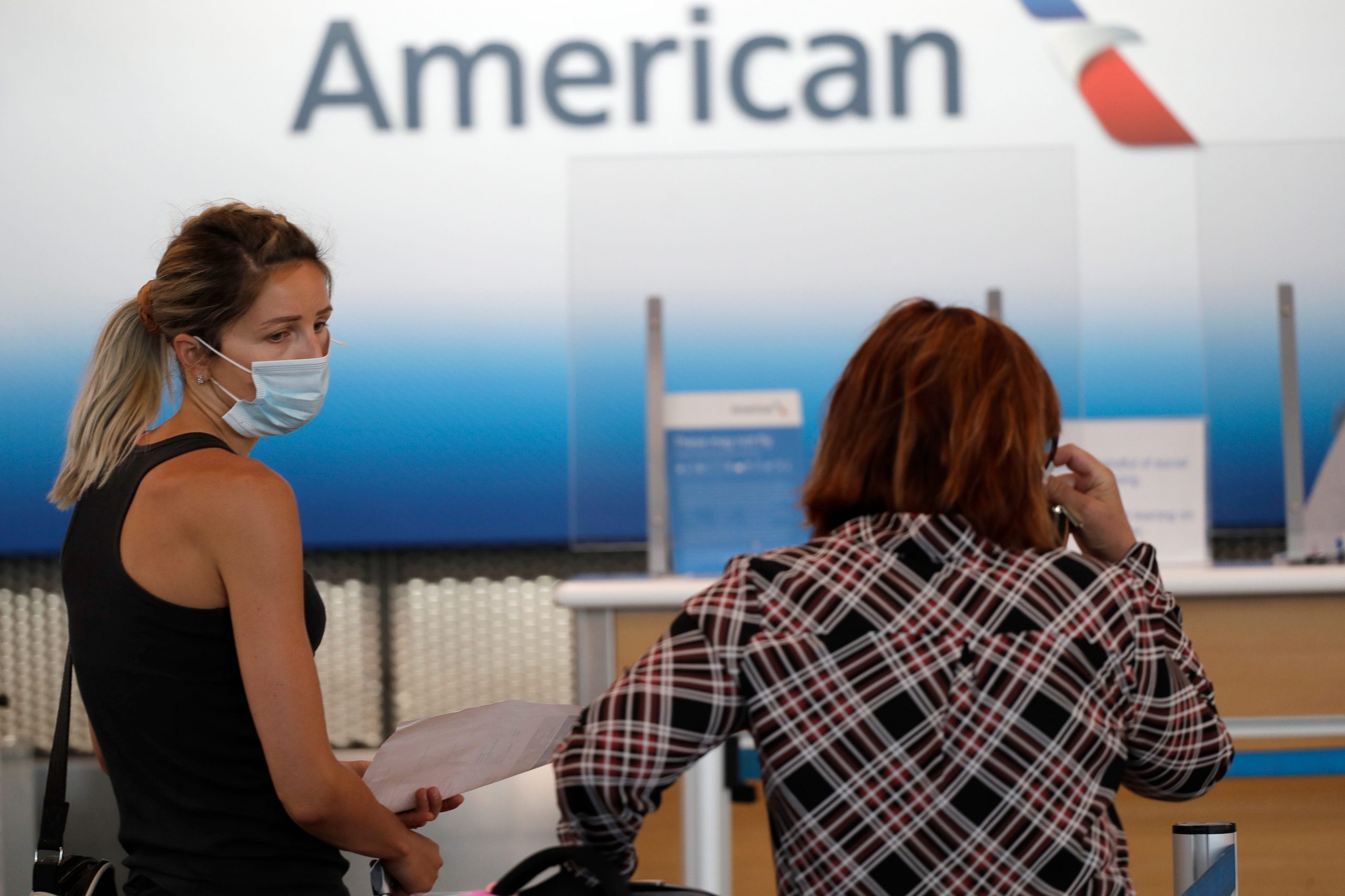 Travelers wear mask as they wait at the American Airlines ticket counter in Terminal 3 at O'Hare International Airport Tuesday, June 16, 2020, in Chicago. Beginning June 16 at American Airlines and June 18 at United Airlines, all passengers and crew members will be required to wear masks to prevent the spread of the coronavirus. (AP Photo/Nam Y. Huh)
