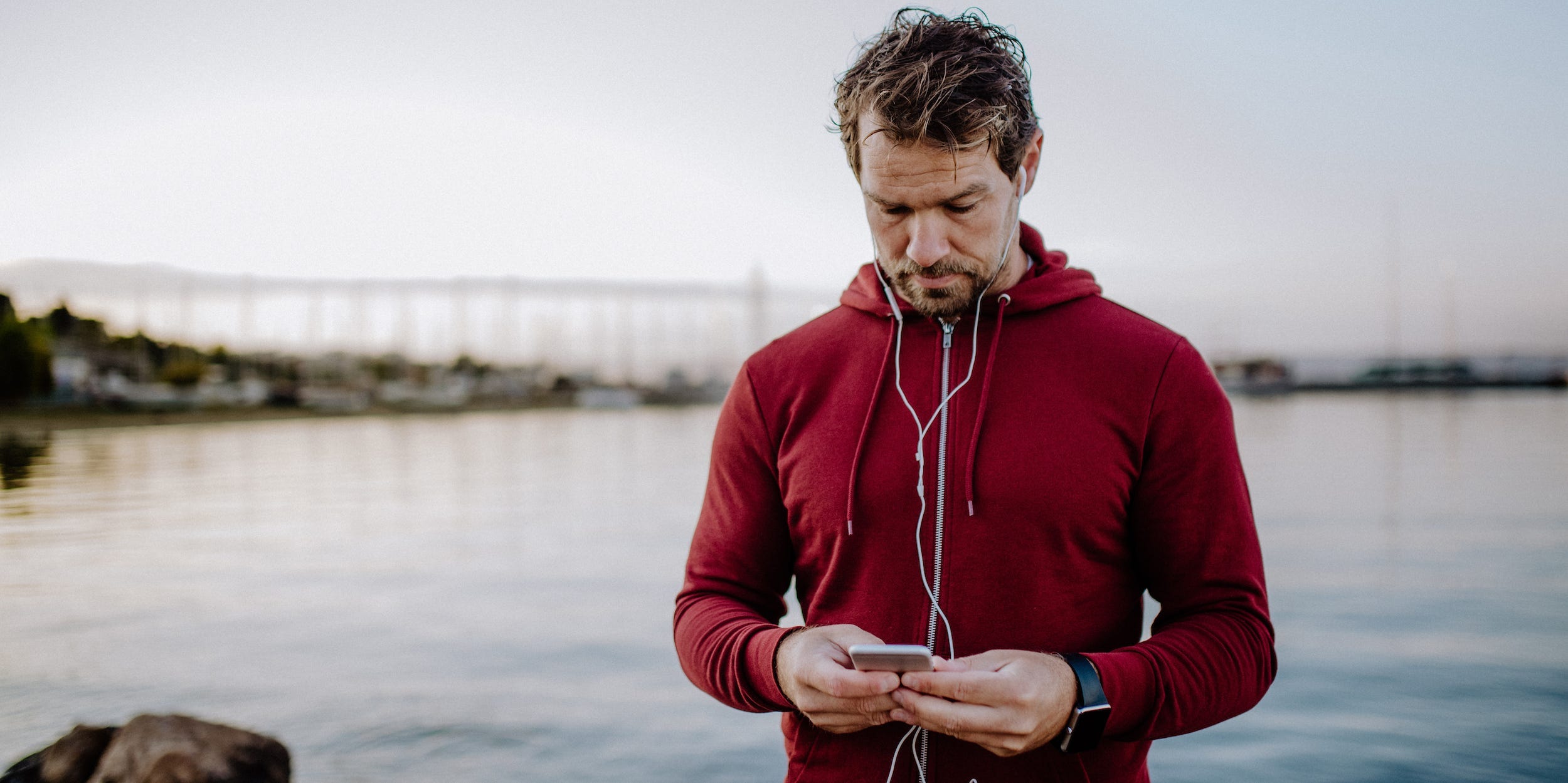 runner man with earphones looking at cell phone water