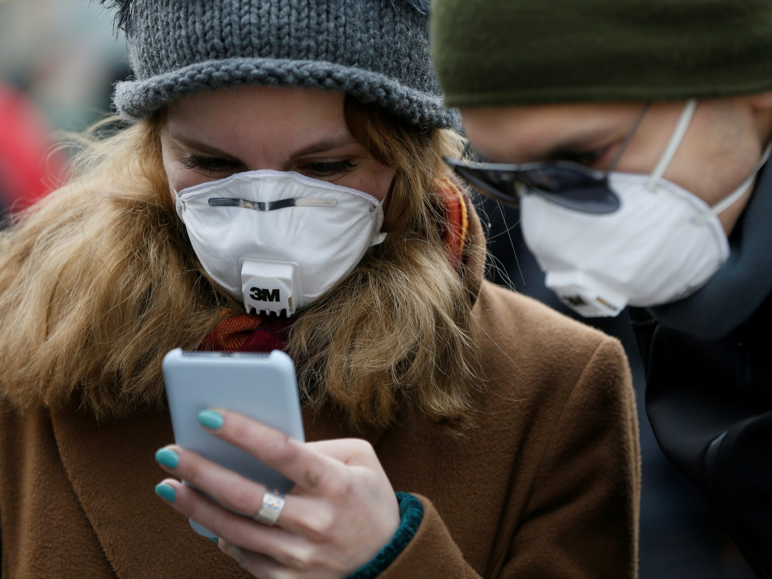 FILE PHOTO: People wearing protective face masks use a smartphone on a street amid coronavirus (COVID-19) concerns in Kiev, Ukraine March 17, 2020.  REUTERS/Valentyn Ogirenko
