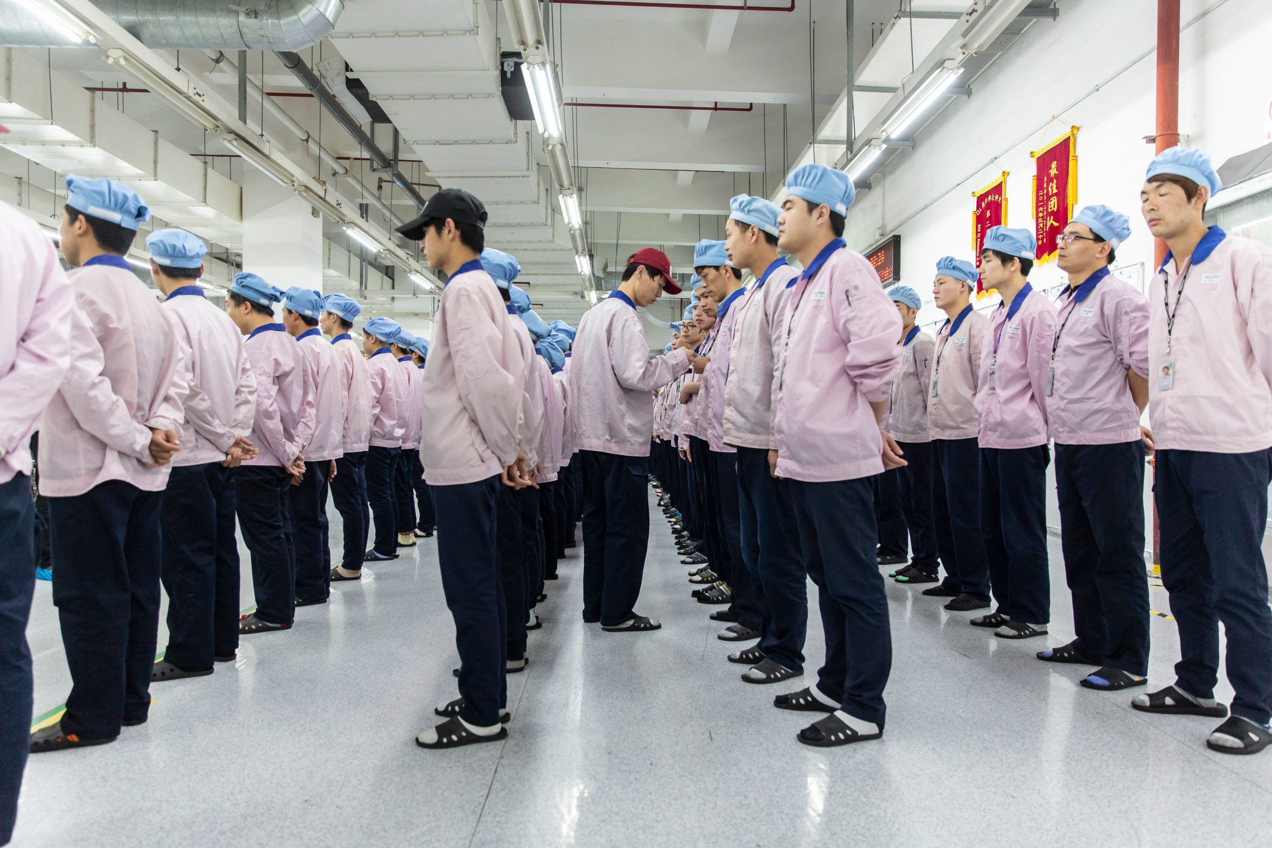 Employees line up for row call before their shift starts at a Pegatron Corp. factory in Shanghai, China, on Friday, April 15, 2016. This is the realm in which the world's most profitable smartphones are made, part of Apple Inc.'s closely guarded supply chain.