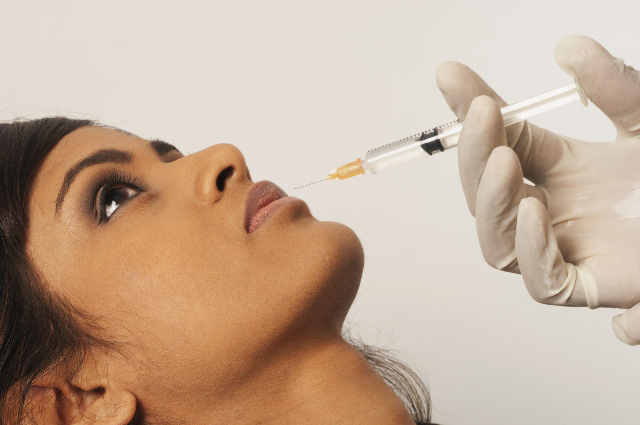Doctor injecting collagen into young womans lip