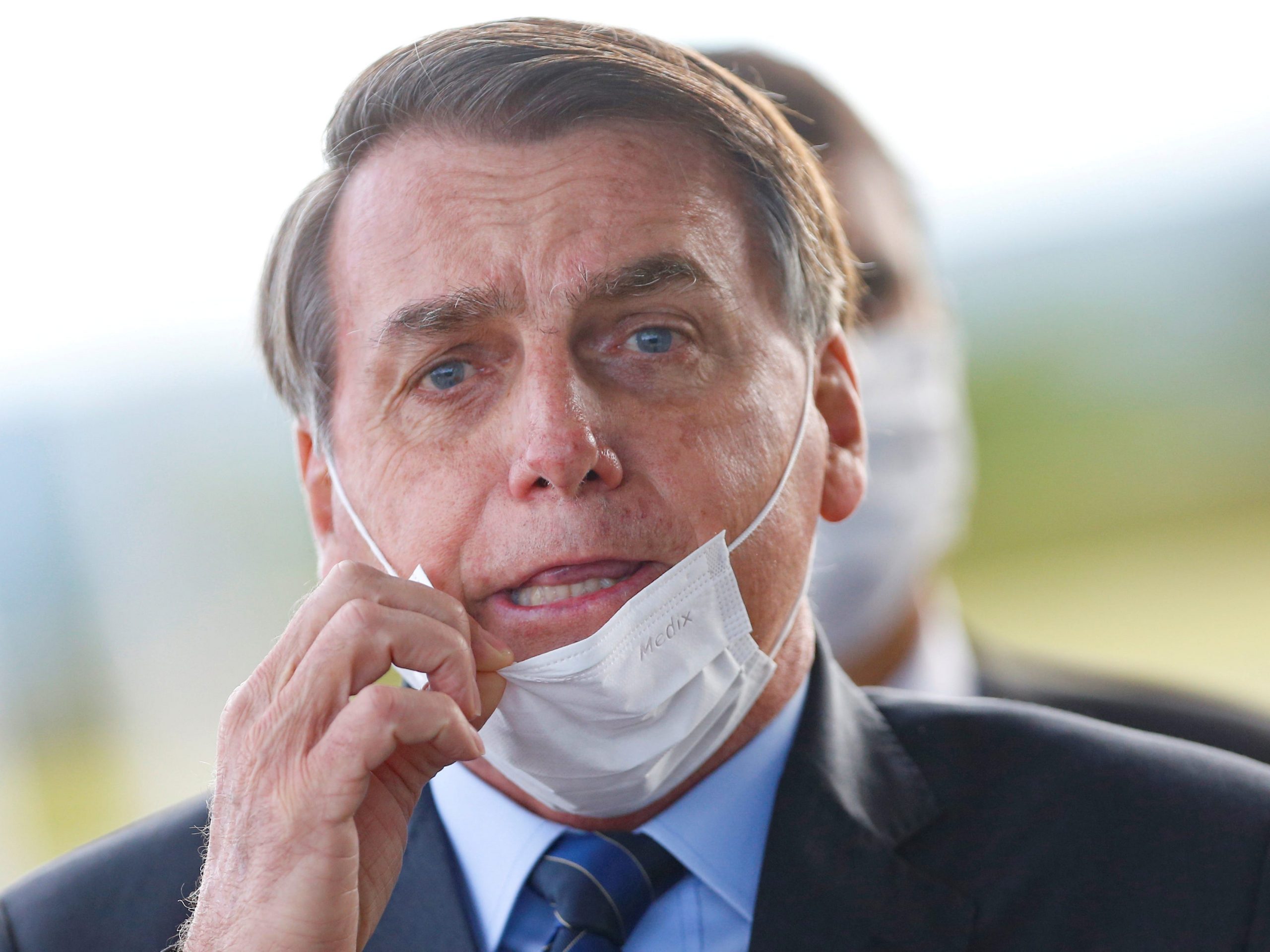 FILE PHOTO: Brazil's President Jair Bolsonaro adjusts his mask as he leaves Alvorada Palace, amid the coronavirus disease (COVID-19) outbreak in Brasilia, Brazil May 13, 2020. REUTERS/Adriano Machado     